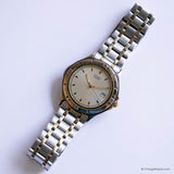 Silver wristwatch with a white face on a light purple background