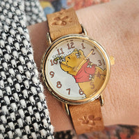 Wristwatch with a cartoon character on the dial, worn on a wrist.