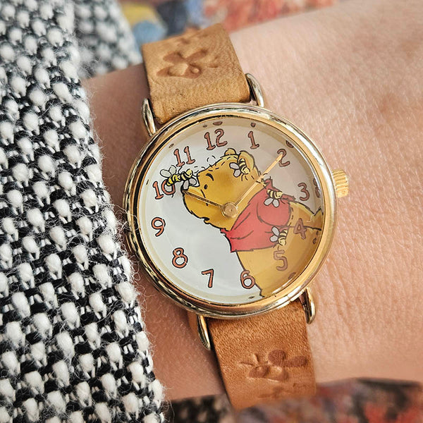 Wristwatch with a cartoon character on the dial, worn on a wrist.