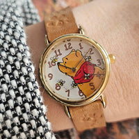 Watch with a cartoon character on the face, worn on a wrist.