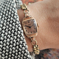 Vintage rose-gold Elgin watch on the wrist with rectangular case and slim bracelet