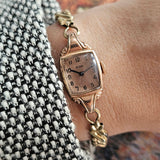 Vintage rose-gold Elgin watch on the wrist with rectangular case and slim bracelet