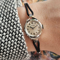 Vintage wristwatch with black strap on a person's wrist, close-up shot.