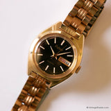 Gold wristwatch with black dial on a white background
