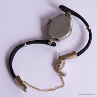 Vintage watch with black cord strap on a light purple background