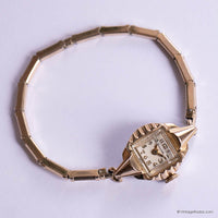 Gold bracelet with a vintage watch face on a light purple background