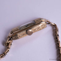 Vintage gold wristwatch on a light purple background