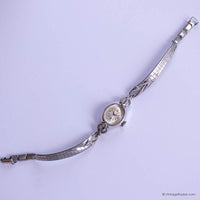 Silver wristwatch with decorative band on a light purple background