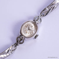 Silver wristwatch with intricate design on a light purple background