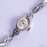 Silver wristwatch with intricate design on a light purple background