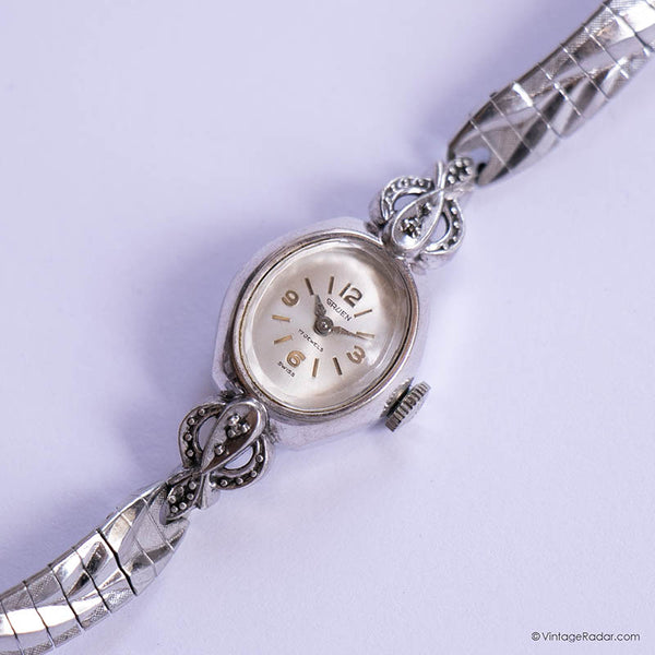 Silver wristwatch with intricate design on a light purple background