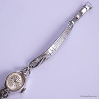 Silver wristwatch with decorative band on a light purple background