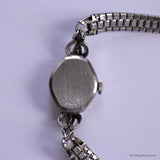 Close-up of a silver watch with a chain on a light purple background